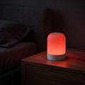 Nightful red glow wind-down lamp glowing warm red on a wooden nightstand next to a bed