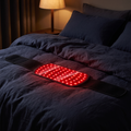 Nightful red light comfort belt with glowing LED panel on dark navy bedding