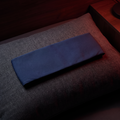 Nightful deep-sleep blackout mask band — flat navy fabric band on a charcoal pillow